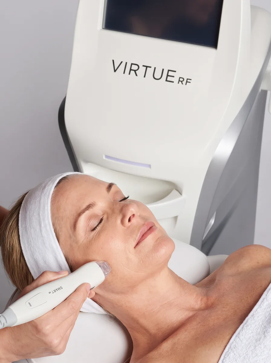 A person receiving a Virtue RF facial treatment beside the device